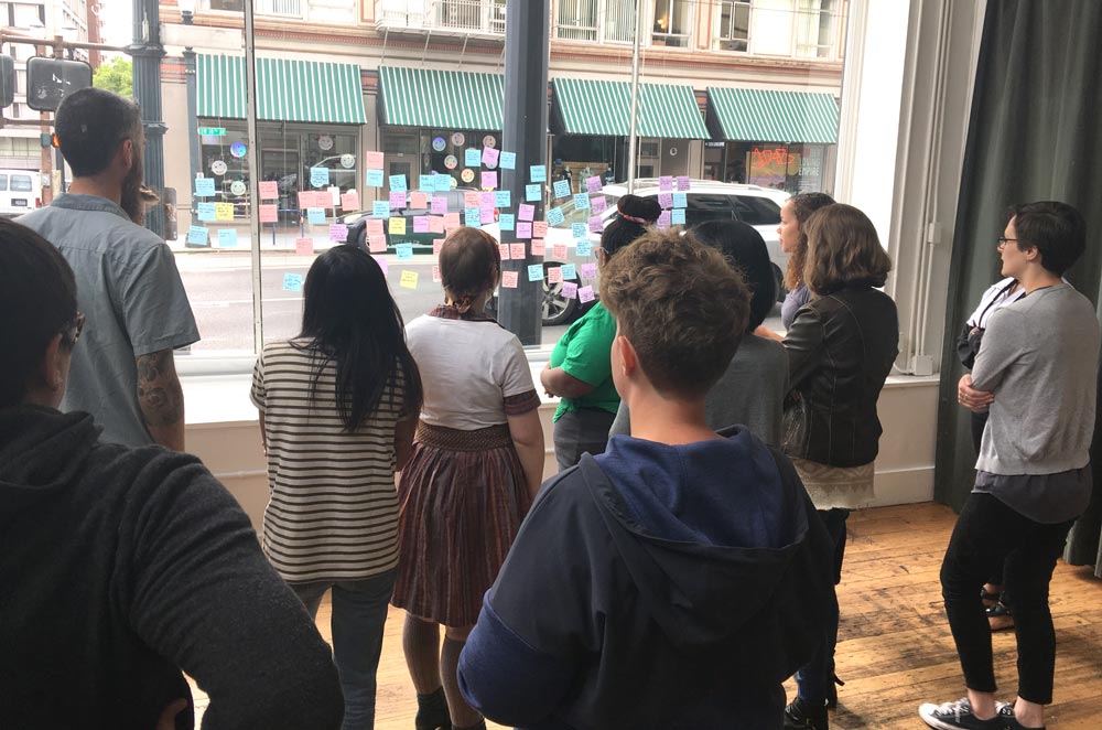 Team members sticking post-its on a window to gather ideas - one of three